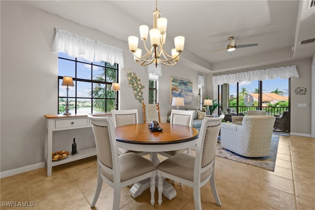 tiled dining room with ceiling fan with notable chandelier and a wealth of natural light