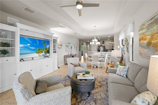 tiled living room with a tray ceiling and ceiling fan with notable chandelier