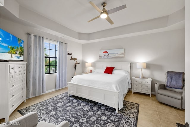 bedroom with ceiling fan, light tile patterned floors, and a tray ceiling