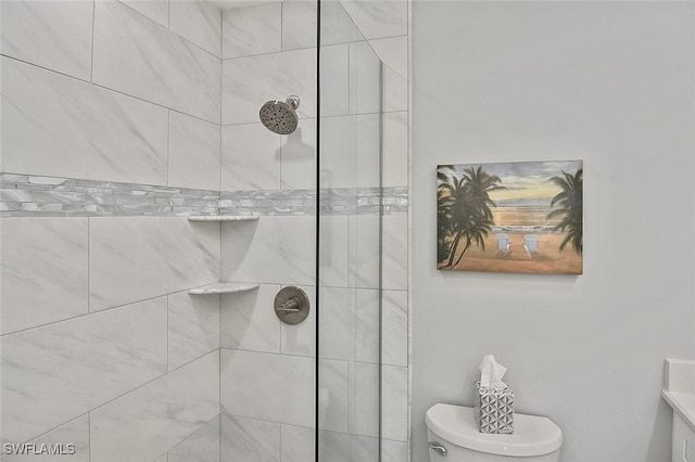 bathroom with vanity, toilet, and tiled shower