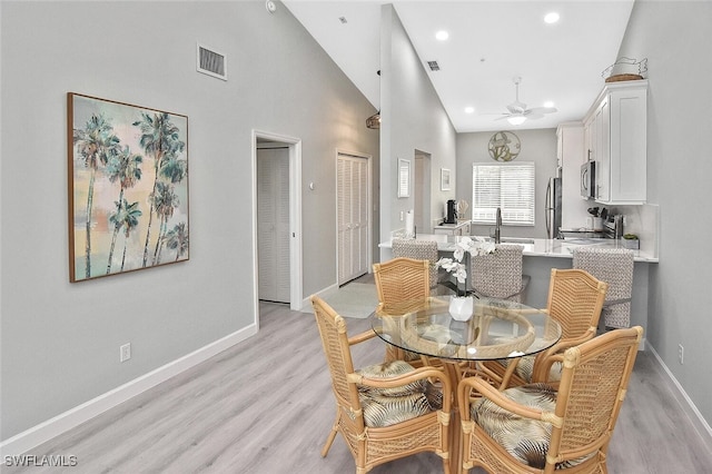 dining area with high vaulted ceiling, light hardwood / wood-style floors, and ceiling fan