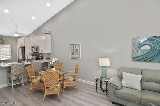 dining space featuring high vaulted ceiling, light wood-type flooring, and ceiling fan