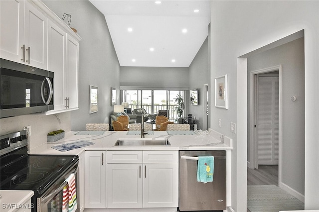 kitchen with white cabinets, sink, high vaulted ceiling, appliances with stainless steel finishes, and light wood-type flooring