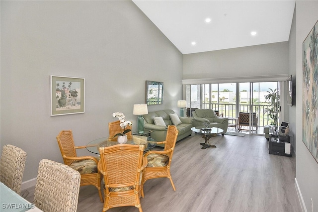 dining area featuring light wood-type flooring and high vaulted ceiling