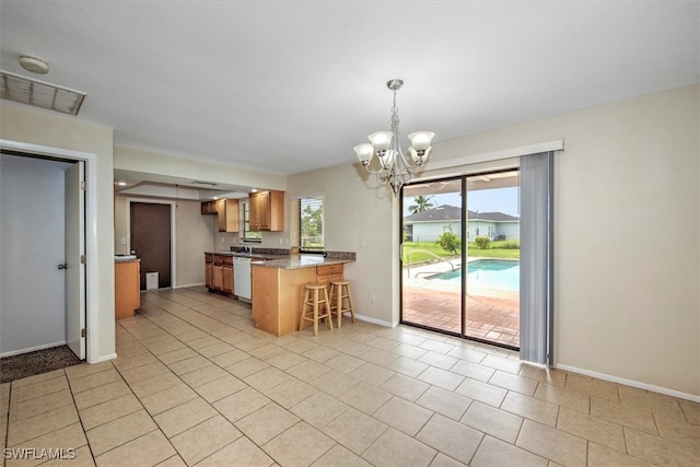 kitchen featuring light tile patterned flooring, kitchen peninsula, hanging light fixtures, an inviting chandelier, and white dishwasher