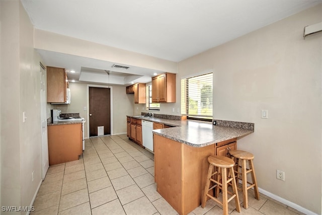 kitchen with sink, kitchen peninsula, a kitchen bar, white appliances, and light tile patterned floors