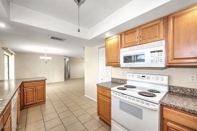 kitchen featuring a raised ceiling, light tile patterned floors, white appliances, decorative light fixtures, and an inviting chandelier