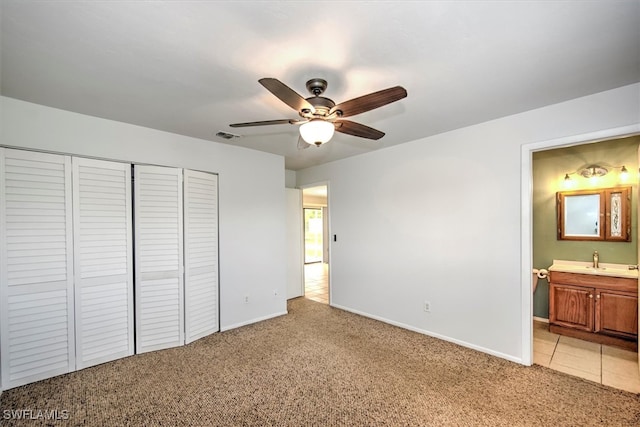 unfurnished bedroom with a closet, sink, light colored carpet, connected bathroom, and ceiling fan