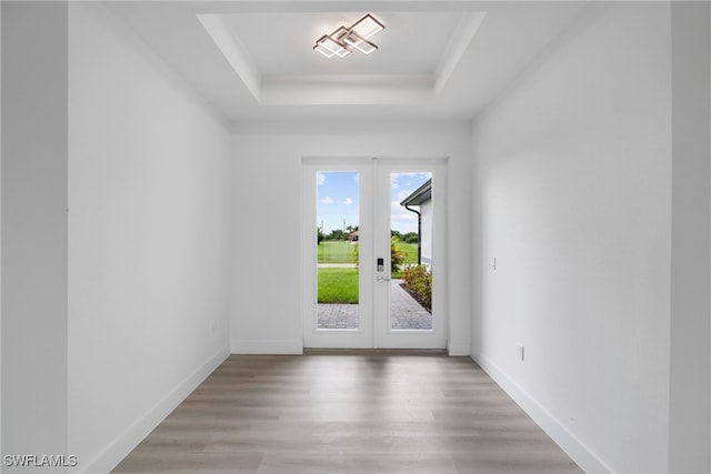 interior space with hardwood / wood-style flooring, a tray ceiling, and french doors