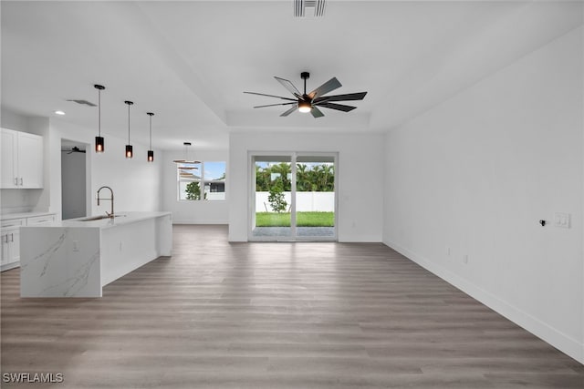 kitchen featuring white cabinets, light stone counters, light wood-type flooring, and sink