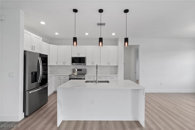 kitchen with white cabinets, sink, stainless steel appliances, and an island with sink