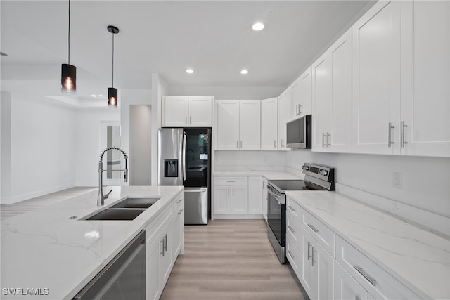 kitchen featuring white cabinets, sink, decorative light fixtures, light stone counters, and stainless steel appliances