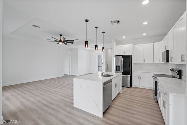 kitchen with sink, white cabinetry, stainless steel appliances, and an island with sink