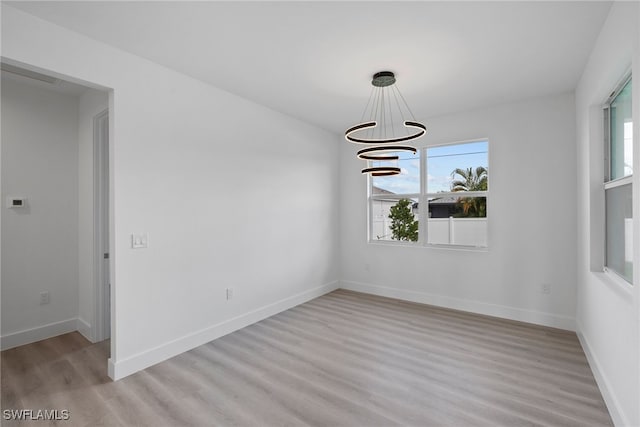 unfurnished dining area with light hardwood / wood-style flooring, a healthy amount of sunlight, and a notable chandelier