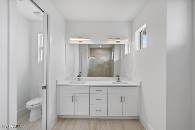 bathroom featuring a shower with door, vanity, hardwood / wood-style floors, and toilet