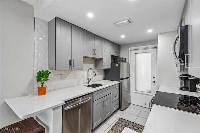 kitchen featuring gray cabinets, sink, decorative backsplash, stainless steel appliances, and light tile patterned floors