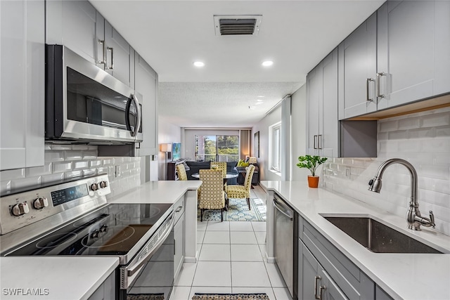 kitchen featuring light tile patterned flooring, appliances with stainless steel finishes, sink, and decorative backsplash