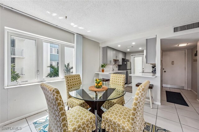 tiled dining room with a textured ceiling and sink