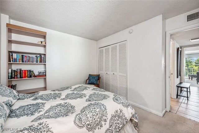 bedroom featuring light carpet, a textured ceiling, and a closet