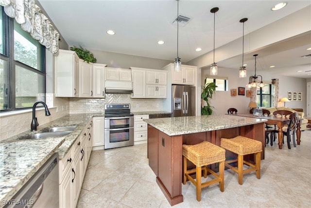 kitchen featuring white cabinets, stainless steel appliances, a breakfast bar, and a center island