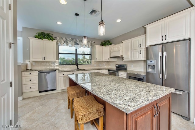 kitchen with a center island, white cabinets, hanging light fixtures, a kitchen breakfast bar, and stainless steel appliances