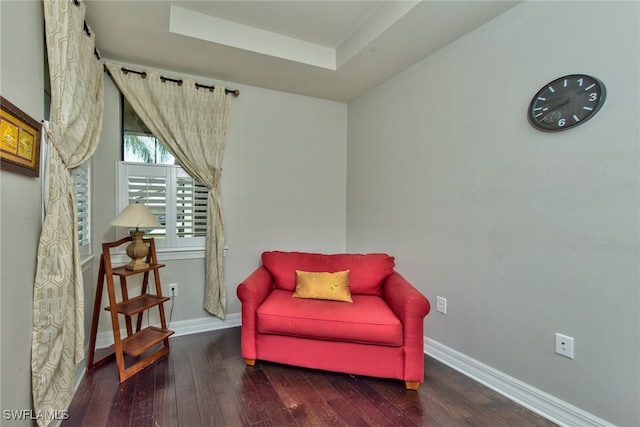 living area featuring a tray ceiling and dark hardwood / wood-style floors