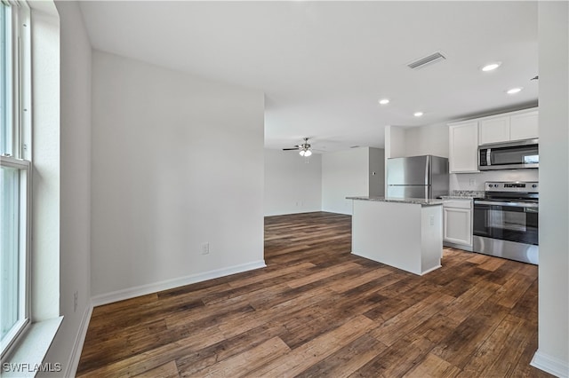 kitchen with dark hardwood / wood-style floors, white cabinets, a kitchen island, appliances with stainless steel finishes, and ceiling fan