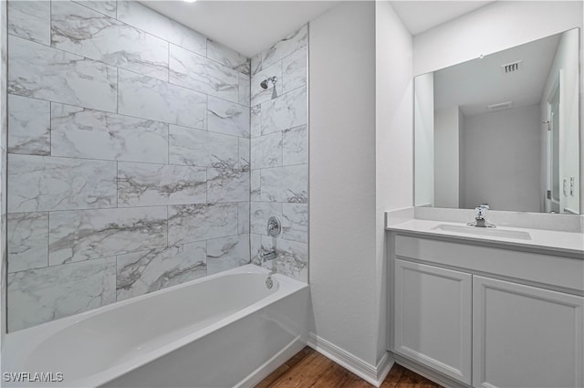 bathroom with wood-type flooring, tiled shower / bath combo, and vanity