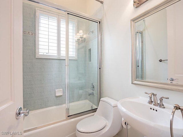 full bathroom featuring toilet, bath / shower combo with glass door, and sink