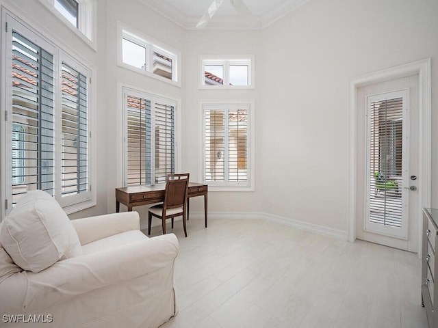 living area featuring a high ceiling, crown molding, and light hardwood / wood-style floors