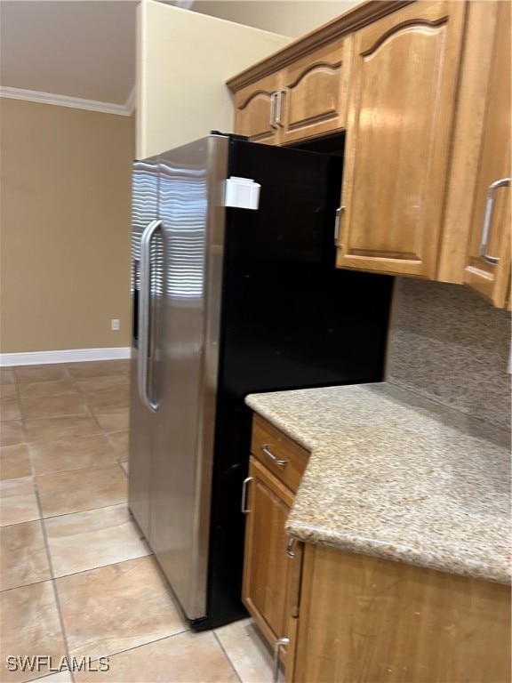 kitchen featuring stainless steel fridge, crown molding, light tile patterned flooring, and light stone countertops