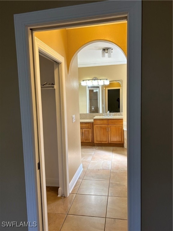 hallway with crown molding, sink, and light tile patterned floors