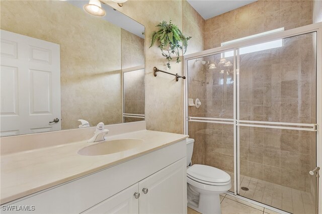 bathroom featuring tile patterned flooring, vanity, toilet, and a shower with door