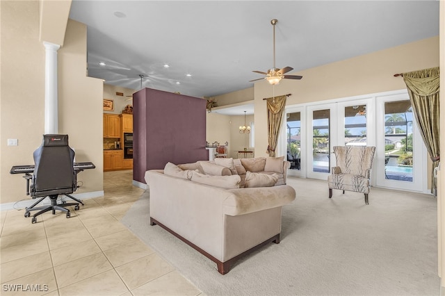 tiled living room featuring ornate columns, french doors, and ceiling fan with notable chandelier