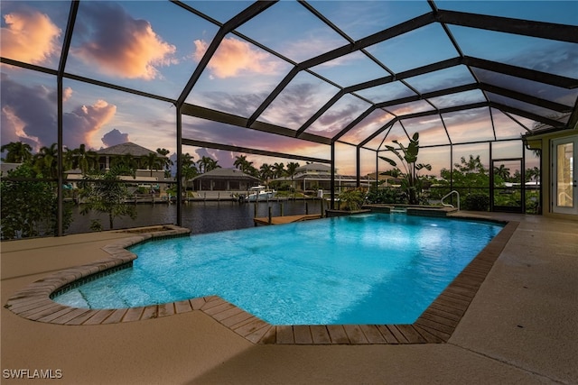 pool at dusk with a water view, glass enclosure, and a patio area