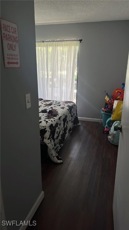 bedroom with a textured ceiling and dark hardwood / wood-style floors