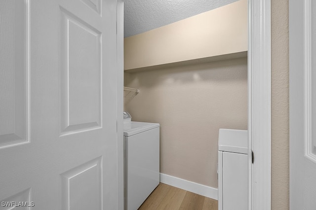 laundry area with a textured ceiling, light hardwood / wood-style flooring, and washing machine and clothes dryer