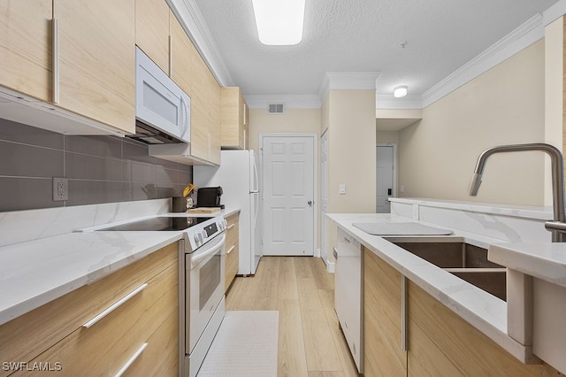 kitchen featuring white appliances, light hardwood / wood-style floors, light stone counters, and crown molding