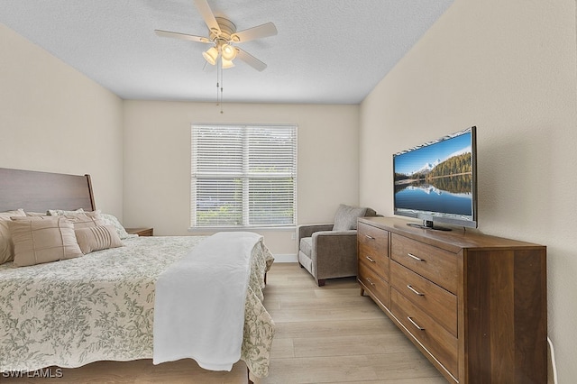 bedroom with light hardwood / wood-style flooring, ceiling fan, and a textured ceiling