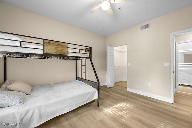 bedroom featuring light hardwood / wood-style flooring, connected bathroom, ceiling fan, and a textured ceiling