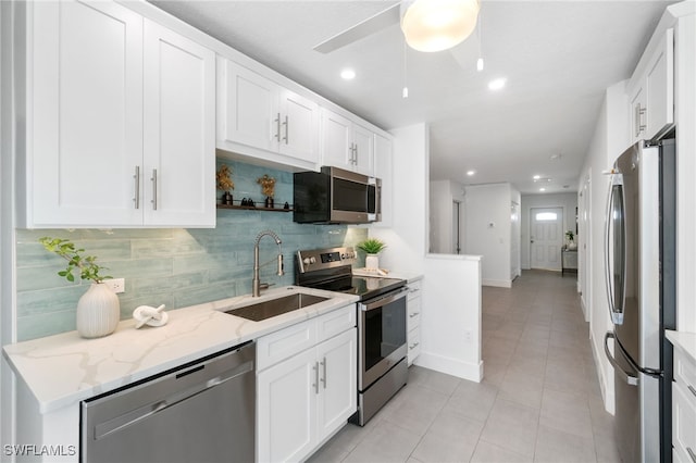 kitchen featuring sink, white cabinets, decorative backsplash, appliances with stainless steel finishes, and ceiling fan