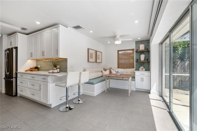 kitchen featuring stainless steel fridge, ceiling fan, and white cabinets