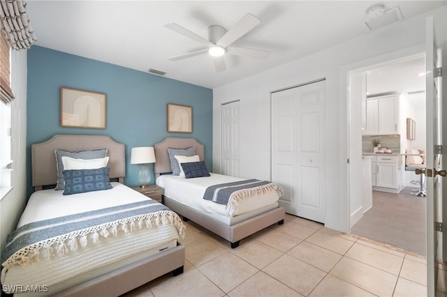 tiled bedroom featuring ceiling fan and two closets