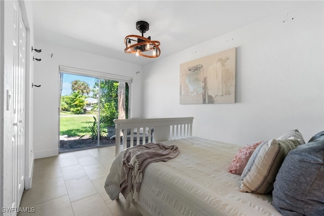 tiled bedroom featuring access to outside and a notable chandelier