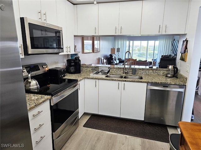 kitchen with white cabinets, sink, light hardwood / wood-style flooring, stainless steel appliances, and light stone countertops