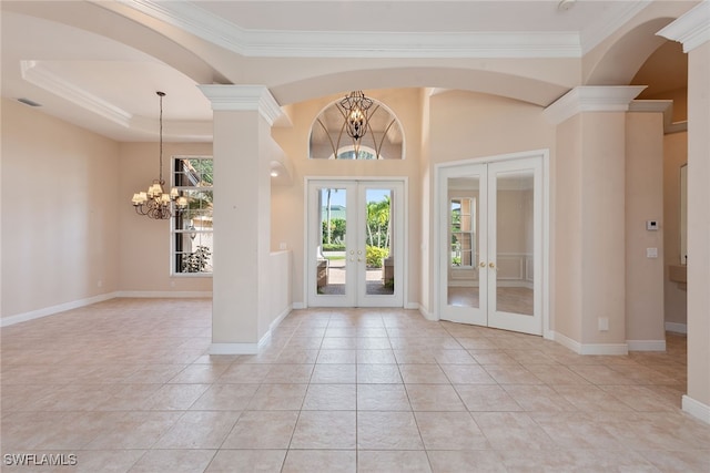 tiled foyer entrance with crown molding, a chandelier, french doors, and ornate columns