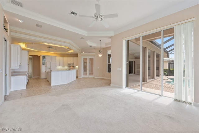 unfurnished living room with ceiling fan, light colored carpet, and crown molding