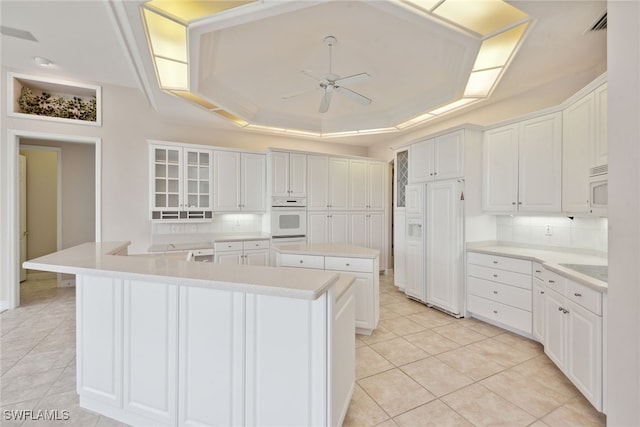 kitchen featuring backsplash, a kitchen island, ceiling fan, and white cabinetry