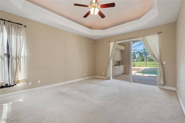 unfurnished room with ceiling fan, a tray ceiling, and light carpet