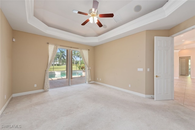 carpeted spare room with a raised ceiling and ceiling fan